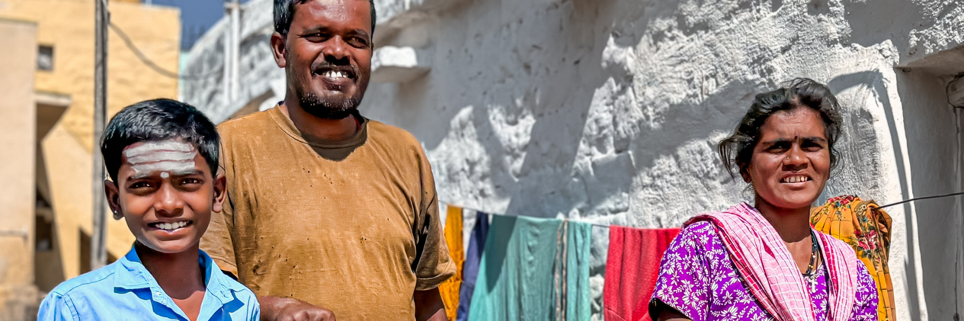 A happy family of three with a visually impaired father who is walking with a guide stick and a young son lends his hand